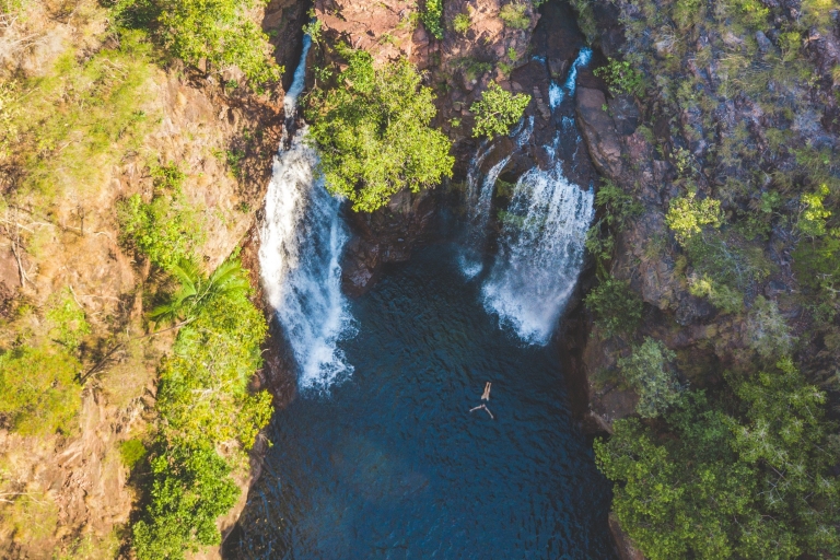 Luftaufnahme einer Person, die sich in einem Naturpool mit blauem Wasser treiben lässt, der von Bäumen umgeben ist und von zwei großen Wasserfällen gespeist wird, Florence Falls, Litchfield National Park, Northern Territory © Tourism NT/Dan Moore Luftaufnahme einer Person, die sich in einem Naturpool mit blauem Wasser treiben lässt, der von Bäumen umgeben ist und von zwei großen Wasserfällen gespeist wird, Florence Falls, Litchfield National Park, Northern Territory © Tourism NT/Dan Moore