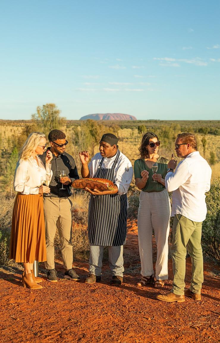 A group of people and a chef sampling food with Uluru in the background, Tali Wiru, Yulara, Northern Territory © Tourism Australia A group of people and a chef sampling food with Uluru in the background, Tali Wiru, Yulara, Northern Territory © Tourism Australia