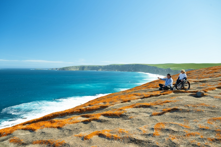 A woman in a wheelchair alongside a tour guide pointing out to blue ocean on Kangaroo Island, South Australia © Tourism Australia