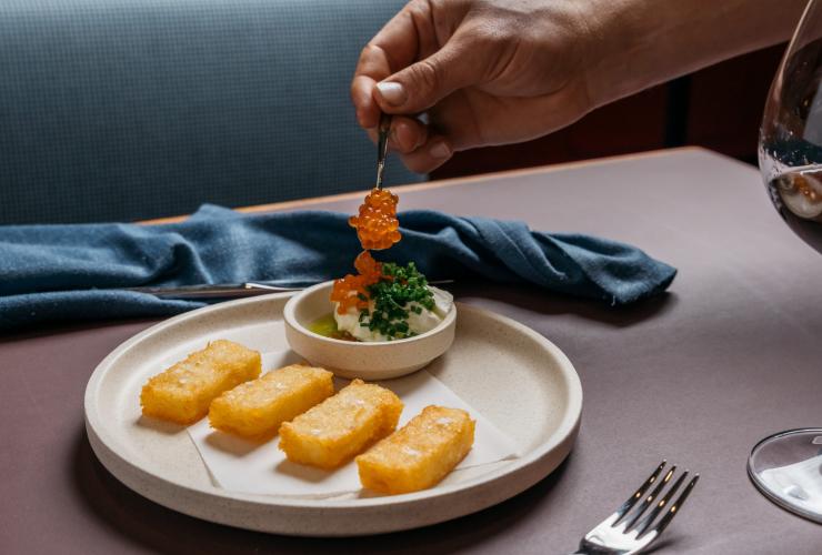 Close up of a hand placing orange fish roe on a carefully plated dish at Fugazzi Bar & Dining Room, Adelaide, South Australia © Julian Cebo Close up of a hand placing orange fish roe on a carefully plated dish at Fugazzi Bar & Dining Room, Adelaide, South Australia © Julian Cebo