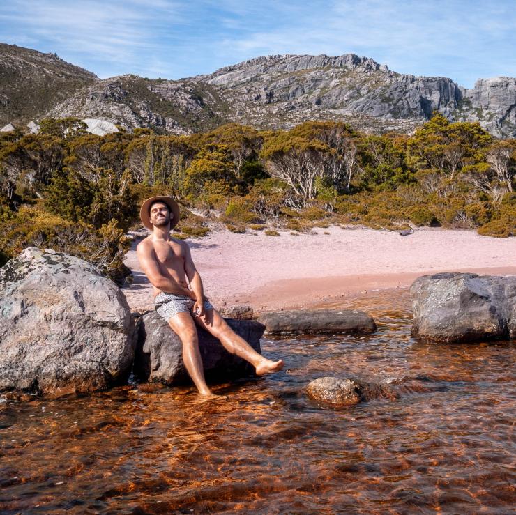 Miles Gray posing on a rock at a lake in West-Coast Tasmania © Miles Gray, @milesuncharted Miles Gray posing on a rock at a lake in West-Coast Tasmania © Miles Gray, @milesuncharted