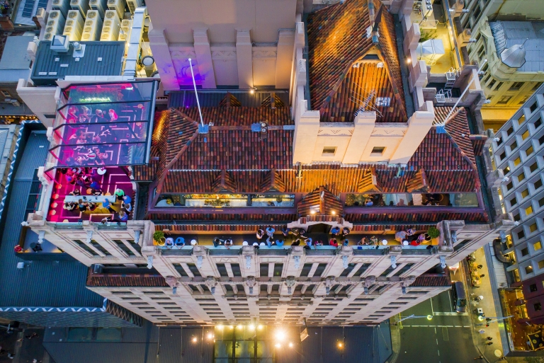 Aerial view over Hennessy Rooftop Bar lit up with pink lights and brimming with people enjoying drinks above the Mayfair Hotel, Adelaide, South Australia © Mayfair Hotel Aerial view over Hennessy Rooftop Bar lit up with pink lights and brimming with people enjoying drinks above the Mayfair Hotel, Adelaide, South Australia © Mayfair Hotel