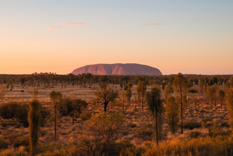 Un immense monolithe de roche rouge dressé sur une plaine de l'arrière-pays à Uluru, Uluru-Kata Tjuta National Park, Territoire du Nord © Tourism Australia