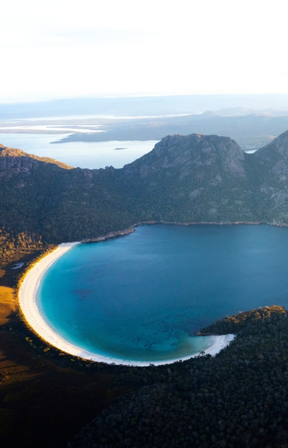 Vue aérienne de Wineglass Bay et des montagnes environnantes boisées au Freycinet National Park, Tasmanie © Lauren Bath
