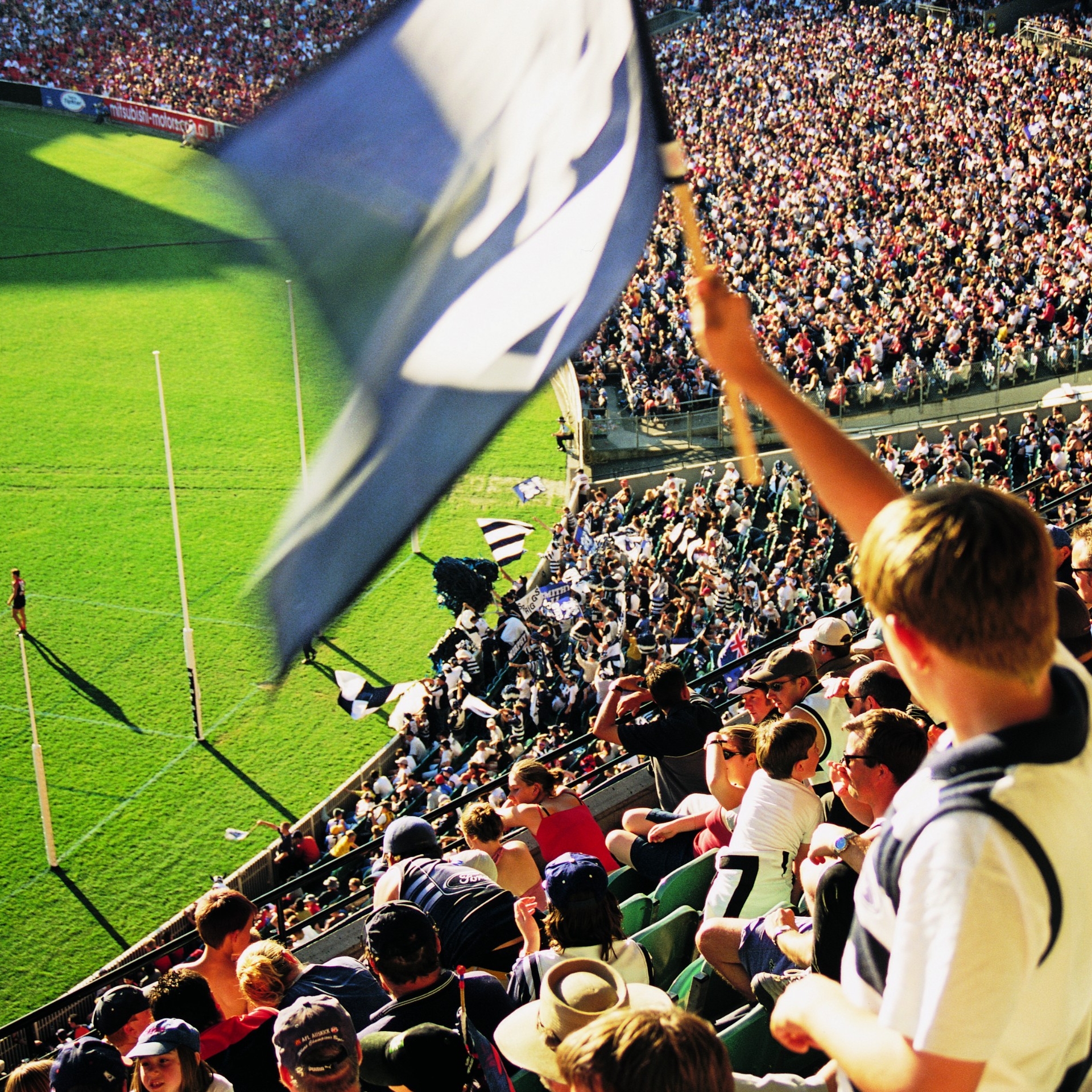 Penggemar mengibarkan bendera di grand final AFL di Melbourne © Tourism Victoria