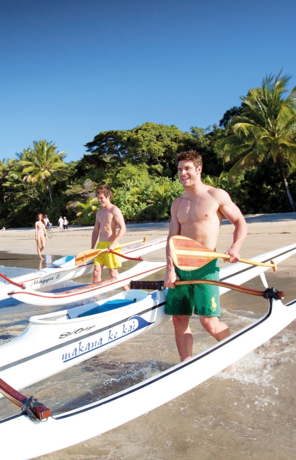 Para pria mendorong perahu ke dalam samudra di Four Mile Beach di dekat Port Douglas © Tourism Port Douglas and Daintree