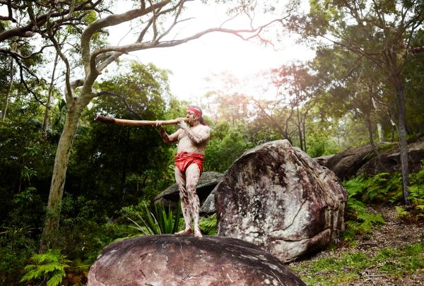 Pria memainkan didgeridoo di atas batu, Pretty Beach House, Bouddi National Park, NSW © Pretty Beach House