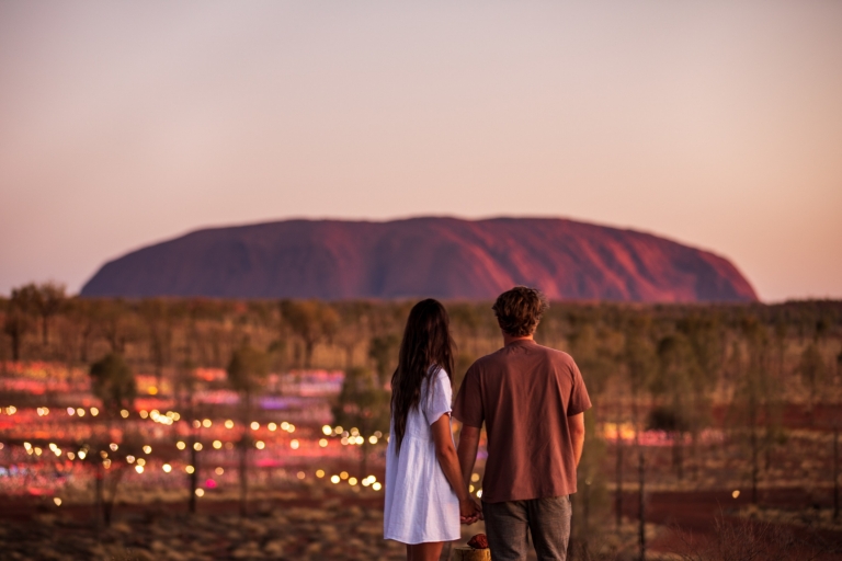 Sepasang wisatawan berdiri di depan Uluru dan Field of Light saat matahari terbenam di Northern Territory © Tourism NT/The Salty Travellers Sepasang wisatawan berdiri di depan Uluru dan Field of Light saat matahari terbenam di Northern Territory © Tourism NT/The Salty Travellers