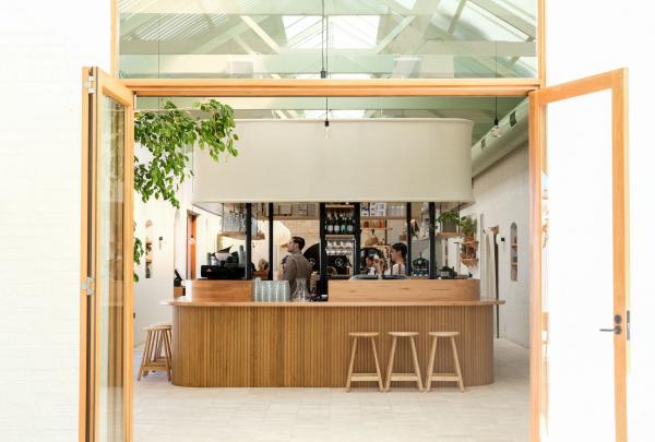 Caffetteria piena di luce con baristi che lavorano dietro a un bancone in legno al Bloom, Adelaide, South Australia © Bloom