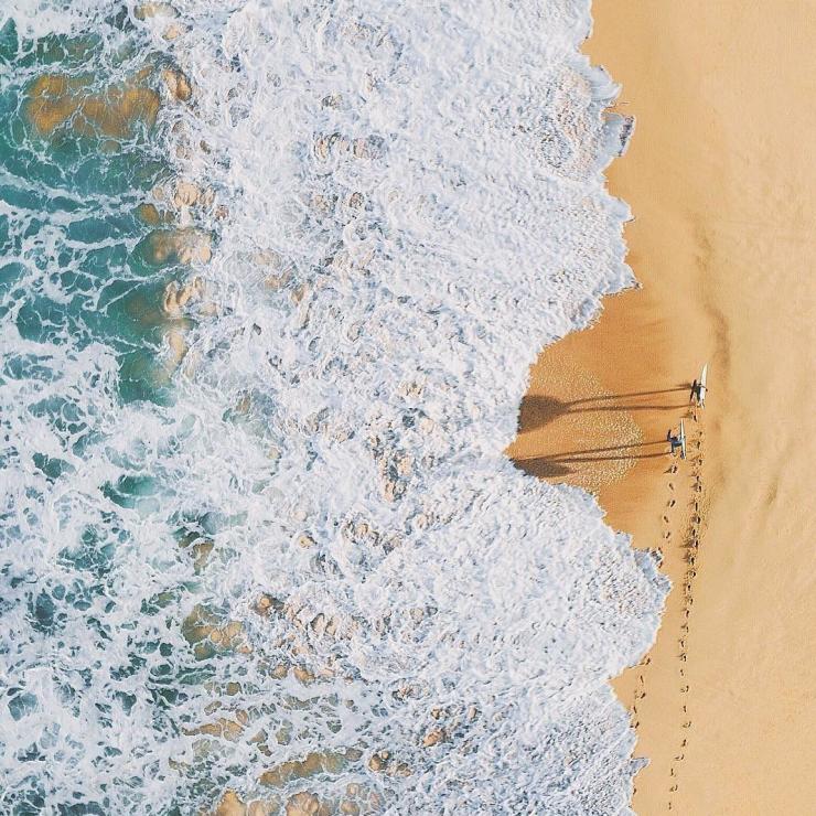 Vista aerea di surfisti che camminano lungo Palm Beach, Sydney © Adam Krowitz Vista aerea di surfisti che camminano lungo Palm Beach, Sydney © Adam Krowitz