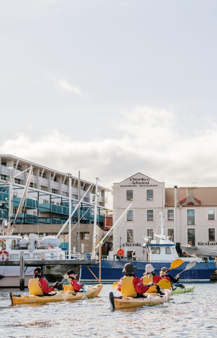 タスマニア州、ホバート、パドルを手にローリング40sカヤッキングの黄色いカヤックをボートが停泊するマリーナで漕ぐ人々 © Tourism Australia タスマニア州、ホバート、パドルを手にローリング40sカヤッキングの黄色いカヤックをボートが停泊するマリーナで漕ぐ人々 © Tourism Australia