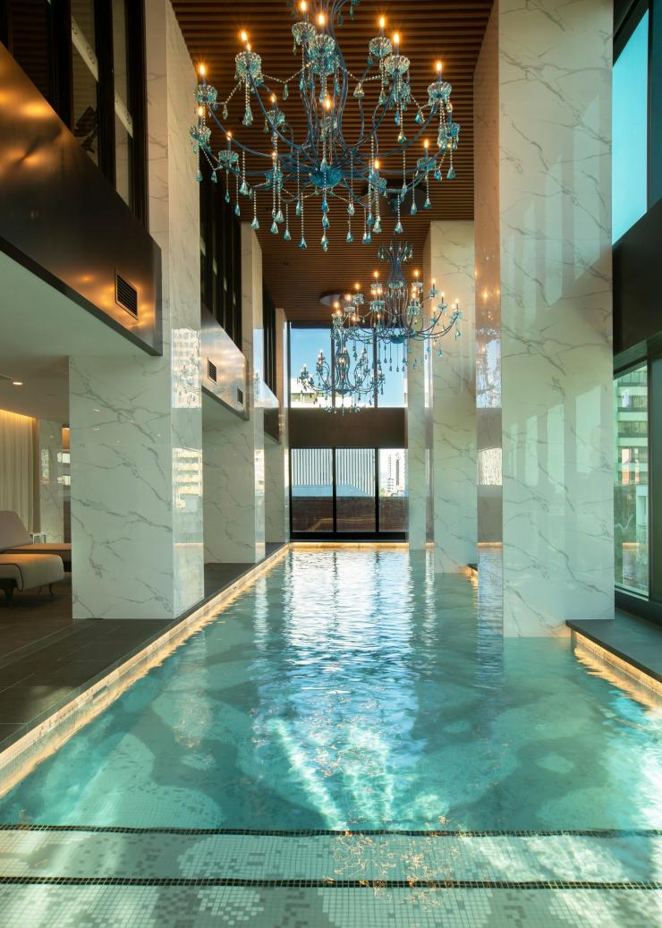 南澳阿德萊德Sofitel Adelaide的游泳池，碧藍色的池水波光粼粼，高樓底建築物內還有白色的大理石柱和藍色的吊燈©Sofitel Adelaide