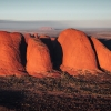 Ein großer Monolith aus rotem Fels erhebt sich aus der flachen Outback-Landschaft am Uluru, Uluru-Kata Tjuta National Park, Northern Territory © Tourism Australia
