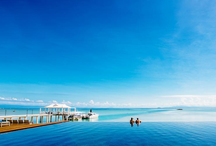 Ein Paar blickt vom Infinity-Pool der Orpheus Island Lodge aus auf den Ozean, Orpheus Island, Queensland © Orpheus Island