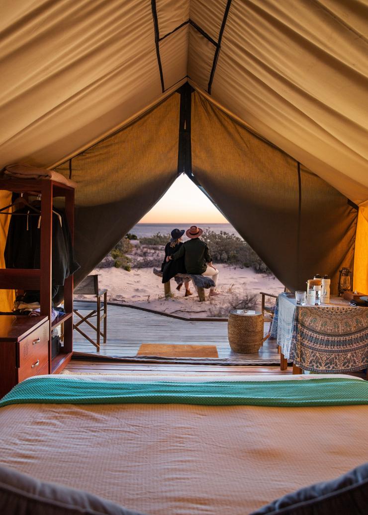 Innenaufnahme eines Luxuszelts von Sal Salis, vor dem ein Pärchen sitzt und den Ausblick auf das Meer und das Ningaloo Reef genießt, Westaustralien © Sal Salis Ningaloo Reef 