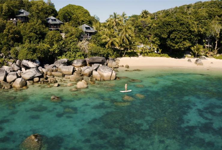 Luftaufnahme der Küste von Bedarra Island mit klarem blauem Wasser, großen Felsbrocken, weißem Sand und grünen Palmen, Great Barrier Reef, Queensland © Tourism Australia