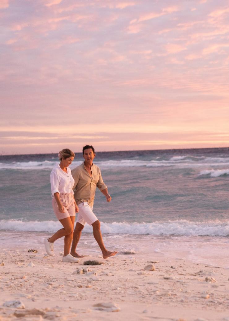 Ein Mann und eine Frau machen bei Sonnenuntergang einen Strandspaziergang am Lady Elliot Island Eco Resort, Great Barrier Reef, Queensland © Tourism and Events Queensland