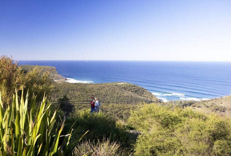 Deux personnes debout sur le Governor Game Lookout, surplombant la verdure bordant l'océan au Royal National Park, Sydney, Nouvelle-Galles du Sud © Destination NSW