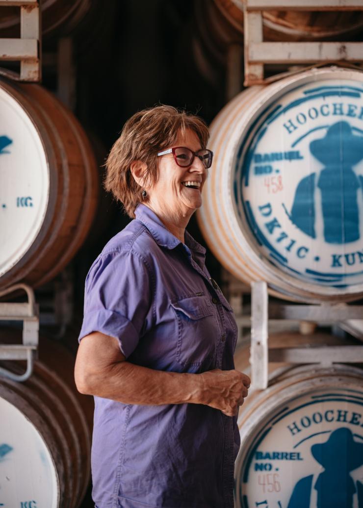 Membre du personnel souriant devant des tonneaux en chêne au Hoochery Distillery Café, Kununurra, Australie Occidentale © Tourism Western Australia