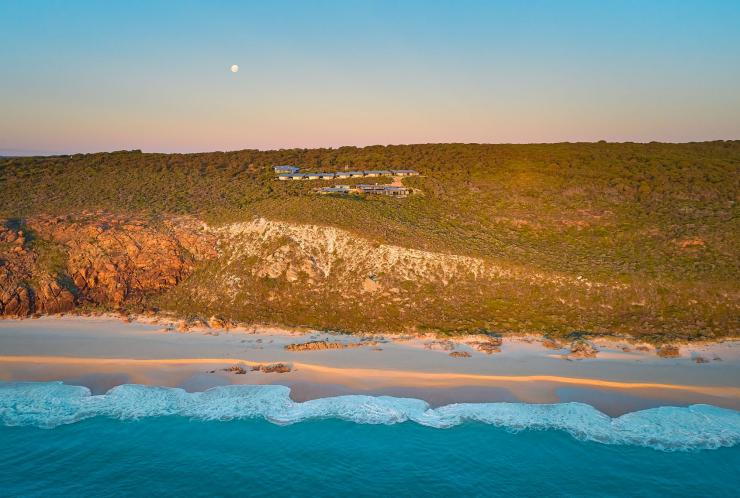 Vue aérienne de l'océan avec l'Injidup Spa Retreat en arrière-plan, perché sur une falaise verdoyante sur le littoral, lors du coucher de soleil laissant apparaître la lune, Margaret River, Australie Occidentale © Injidup Spa Retreat