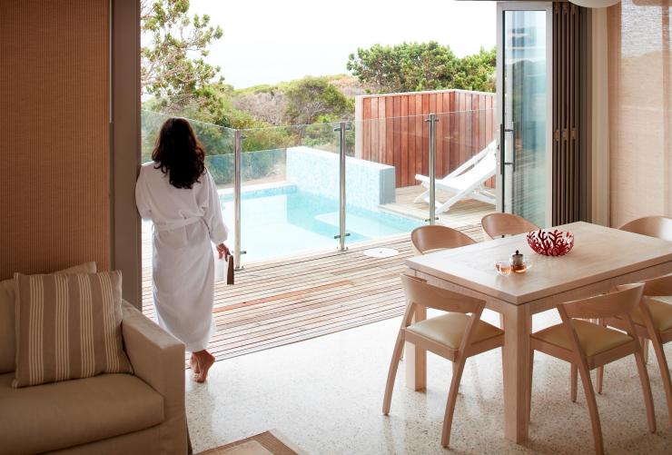 Une femme portant un peignoir appuyée contre l'encadrement de la grande ouverture donnant sur sa terrasse et sa piscine à débordement privées au Injidup Spa Retreat, Margaret River, Australie Occidentale © Injidup Spa Retreat