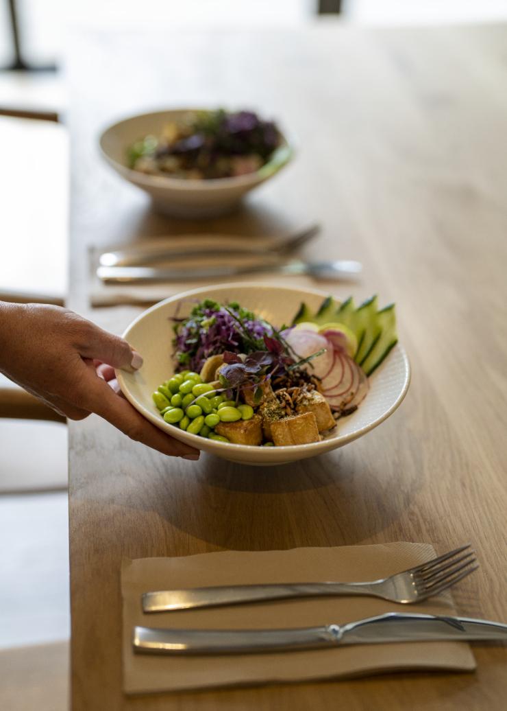 Une main posant un bol de produits frais sur une table au Eden Health Retreat, Currumbin Valley, Queensland © Tourism and Events Queensland