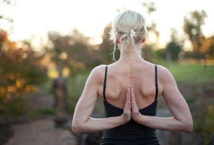 Une personne debout dans le bush exécutant une posture de yoga, ses mains se rejoignant dans son dos, à Samadhi Retreat, Daylesford, Victoria © Samadhi Retreat/Marcus Struzina