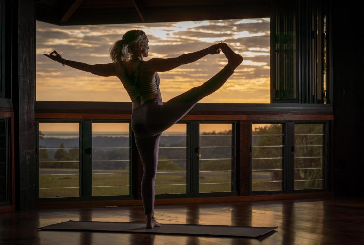 Une femme exécutant une posture de yoga sur un balcon lors du coucher du soleil au Gwinganna Lifestyle Retreat, Tallebudgera Valley, Queensland © Gwinganna Lifestyle Retreat