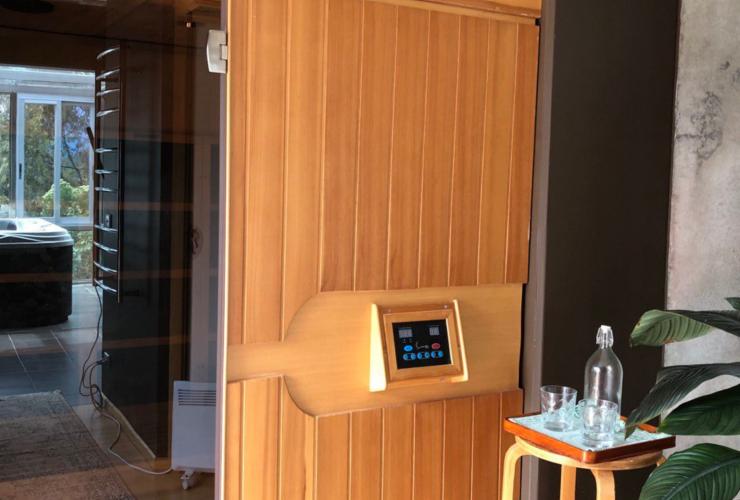 L'extérieur d'un sauna doté d'une porte en bois, avec un jacuzzi en arrière-plan et des verres d'eau au premier plan, au Harmony Hill Health Retreat, Hobart, Tasmanie © Harmony Hill Health Retreat