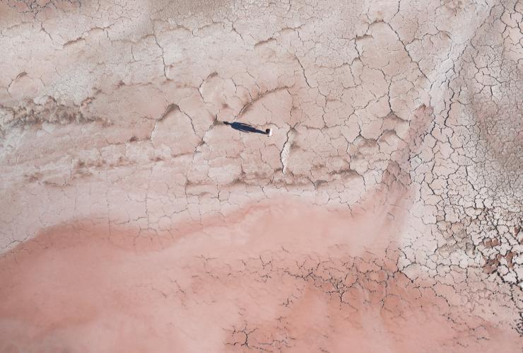 Vue aérienne d'une personne debout qui regarde son ombre se dessiner sur les rives asséchées du Lake MacDonnell rose dans l'Eyre Peninsula, Australie du Sud © Tourism Australia