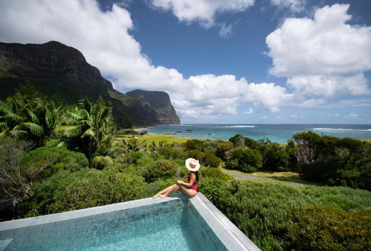 Femme assise au bord d'une piscine avec vue sur le paysage luxuriant à Capella Lodge sur Lord Howe Island, NSW © Tom Archer
