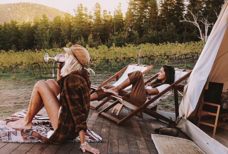 Wanita meminum anggur di luar tenda glamping di Naked Cubby Co di dekat Canberra, ACT © Naked Cubby Co/Shan Bawden