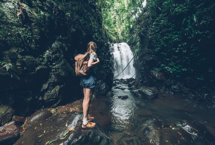 Seorang gadis berdiri menggendong tas ransel di tepi Box Log Falls di Lamington National Park, Queensland © Tourism and Events Queensland
