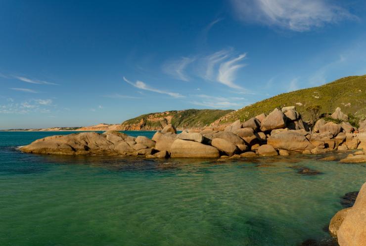 Perairan biru jernih yang dikelilingi oleh batu pasir halus dan bukit padang rumput di Fairy Cove, Wilsons Promontory National Park, Victoria © Mark Watson, Visit Victoria