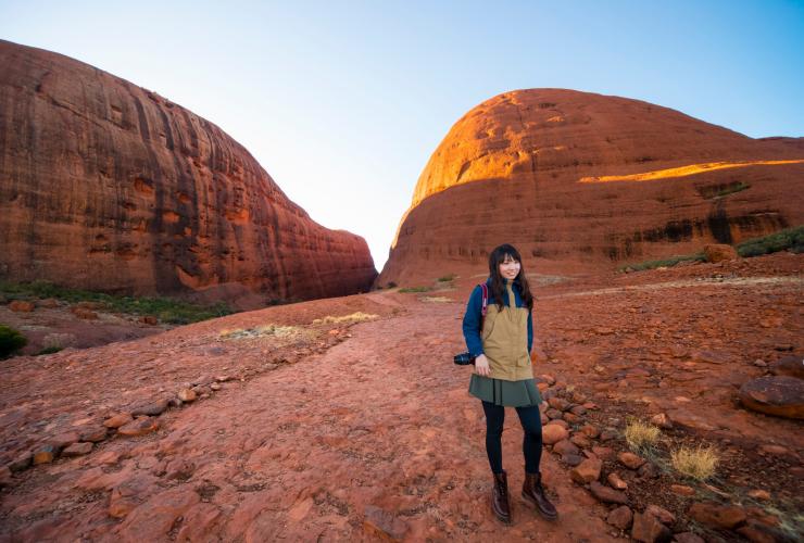 Seseorang wanita berpose di antara dua tebing menjulang pada Valley of the Winds walk, Kata Tjuta, Red Centre, Northern Territory © Tourism NT/Salty Aura