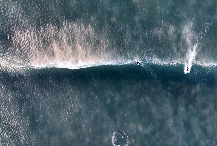 Veduta aerea di surfisti che cavalcano un'onda a Bells Beach, Great Ocean Road, Victoria © Tourism Australia