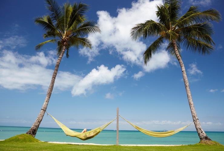 Persona che si rilassa su una delle due amache tra le palme con vista sulla costa bagnata dalle acque cristalline di Orpheus Island presso l'Orpheus Island Lodge, Queensland © Tourism Australia