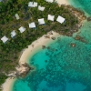 Veduta aerea dell'accomodation Lizard Island Resort tra gli alberi sulla costa di sabbia bianca di Lizard Island, affacciata sul limpido oceano blu nel Queensland © Tourism and Events Queensland