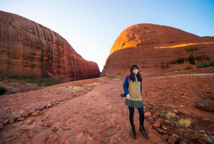 Persona in posa davanti a due maestose scogliere lungo il sentiero Valley of the Winds, Kata Tjuta, Red Centre, Northern Territory © Tourism NT/Salty Aura